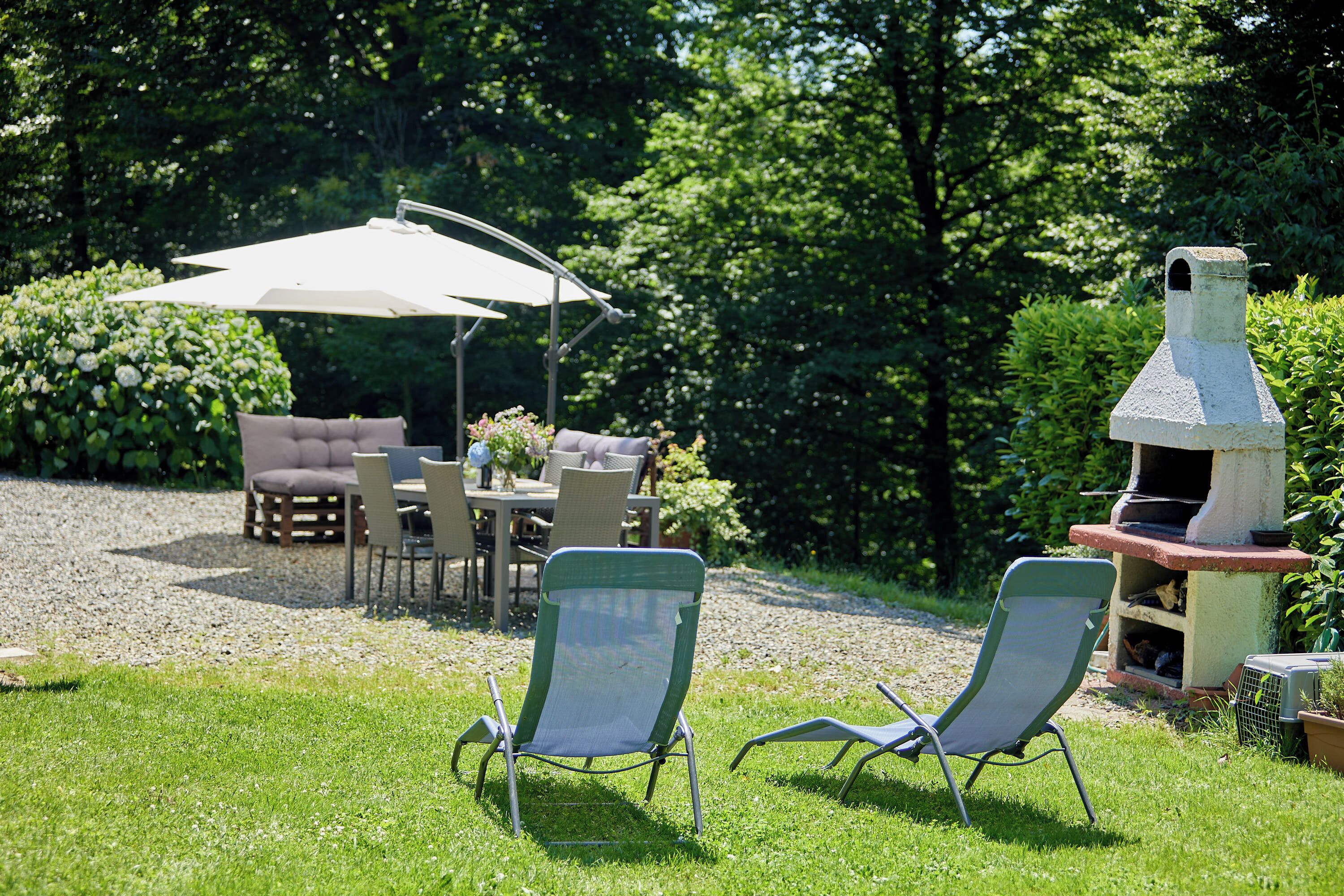 A patio with two lawn chairs, a table with chairs, and a barbecue grill.