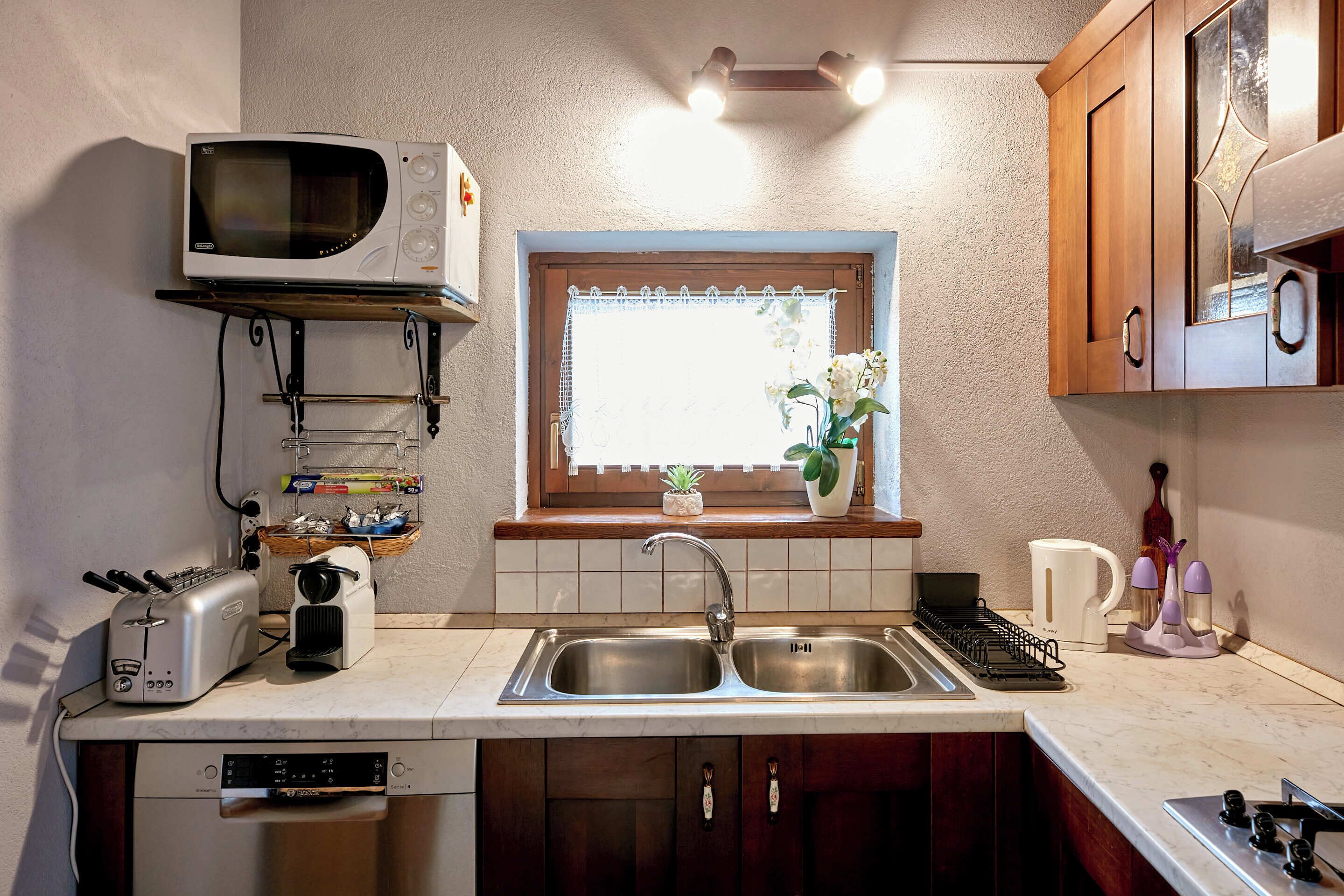 A compact kitchen with a microwave, toaster, sink, and a Bosch dishwasher.