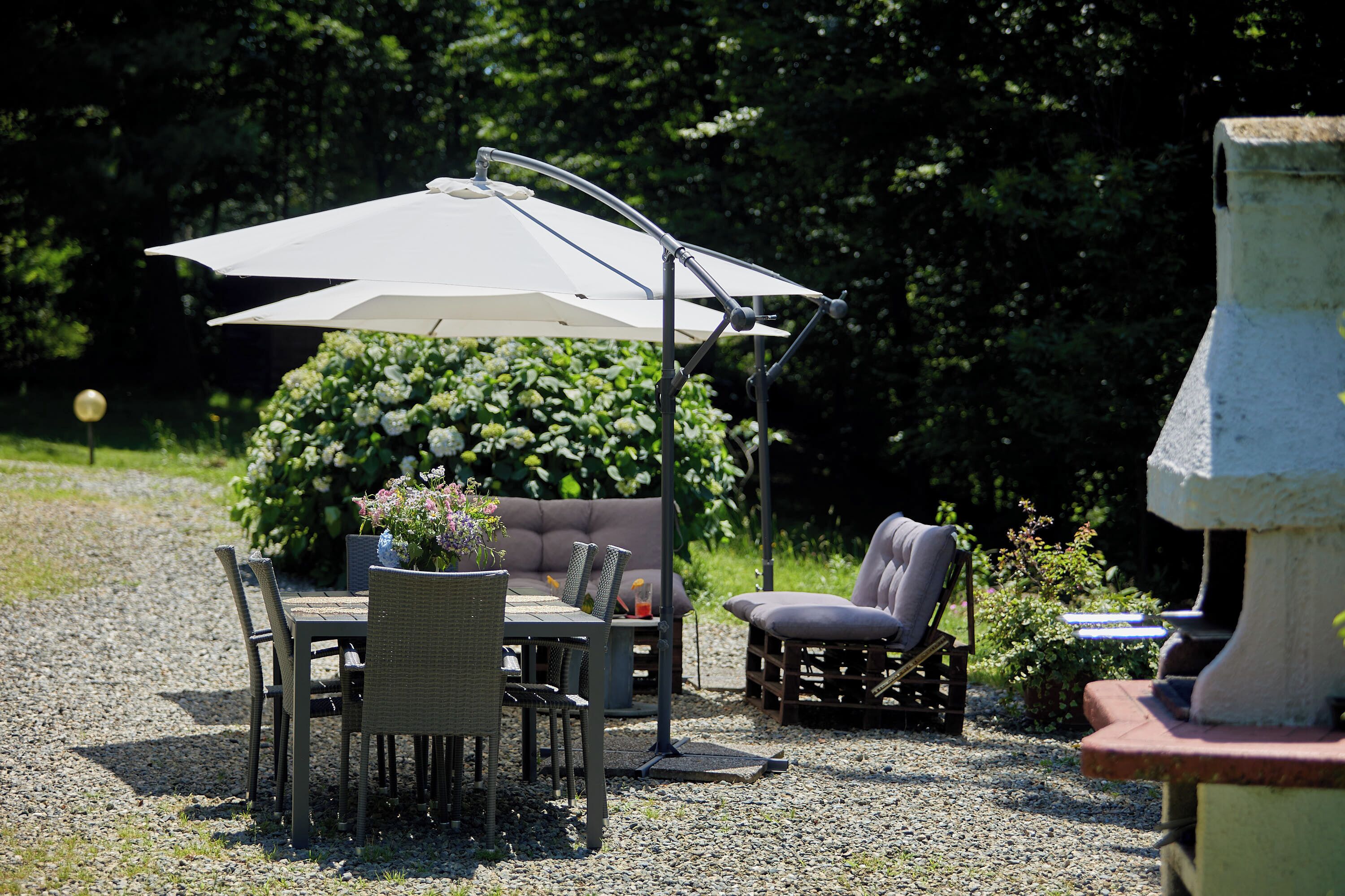Un espace extérieur aménagé avec une table, des chaises et un grand parasol.