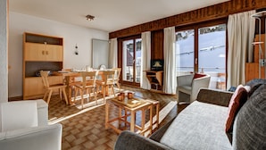 Un salón espacioso con una mesa de comedor de madera, sillas, un sofá y un televisor.