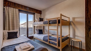 Una habitación con una cama litera, una cama individual y un taburete pequeño.