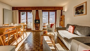 Un salón amplio con una mesa de comedor de madera, asientos cómodos, un sofá y ventanas grandes que ofrecen vistas al exterior.