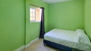A small, single-bed room with green walls and a window with a curtain. - Seagull Suite G - Beach Front Living (Laborie Beach)