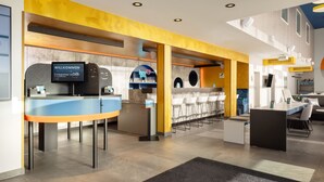 Un hall d’hôtel moderne comprenant un comptoir d’accueil, un espace salon et un bar.