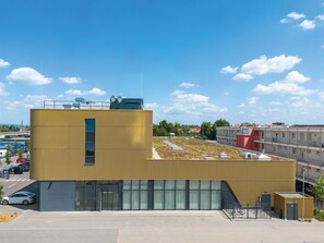 Un edificio moderno con techo plano, ventanas grandes y una estructura pequeña contigua.
