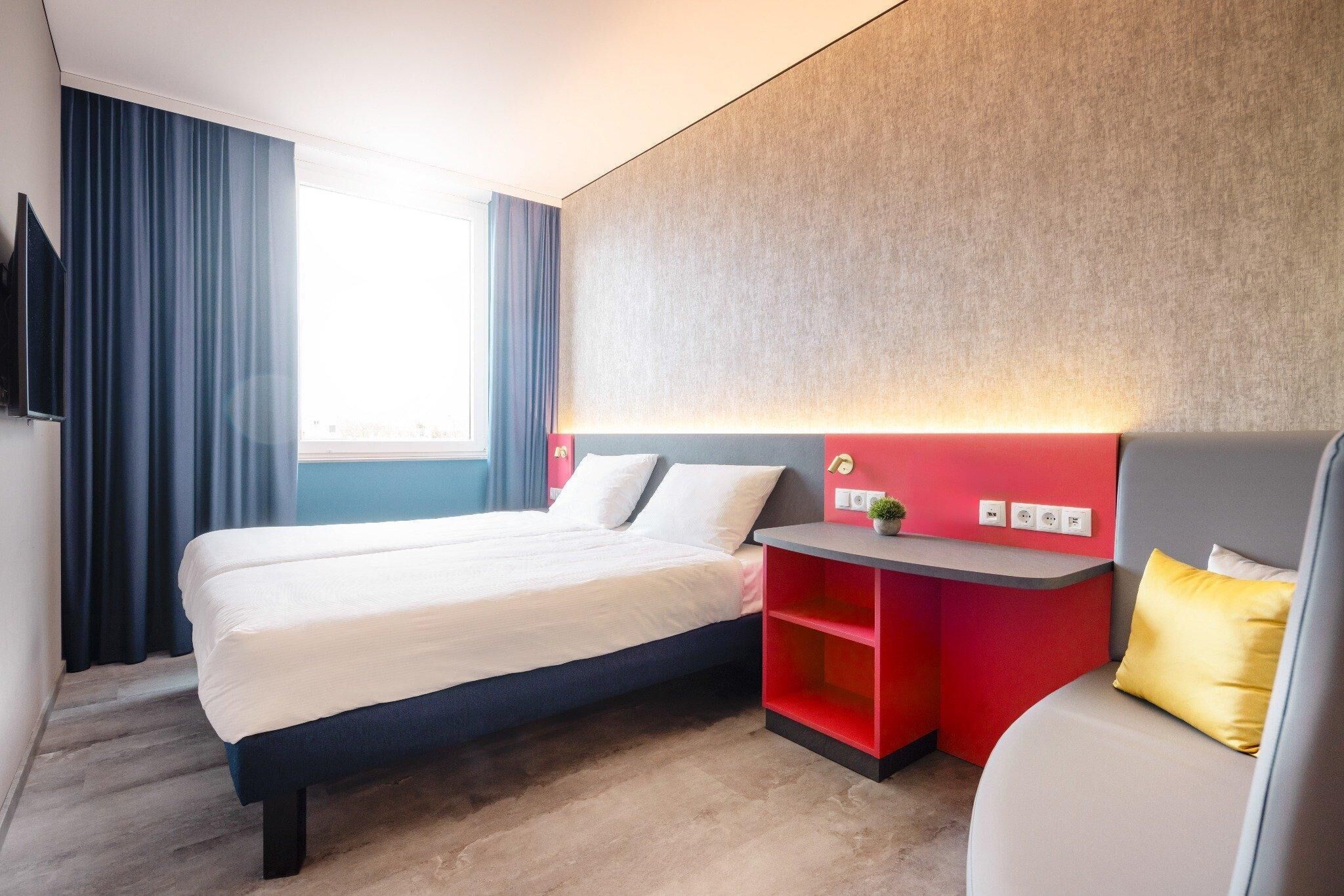 Una habitación de hotel con cama, escritorio y silla.
