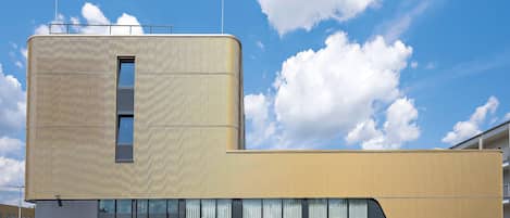 A modern building with a curved facade, large windows, and a flat roof.