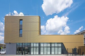 A modern building with a curved facade, large windows, and a flat roof. - Hey Lou Hotel Nördlingen (Nördlingen)