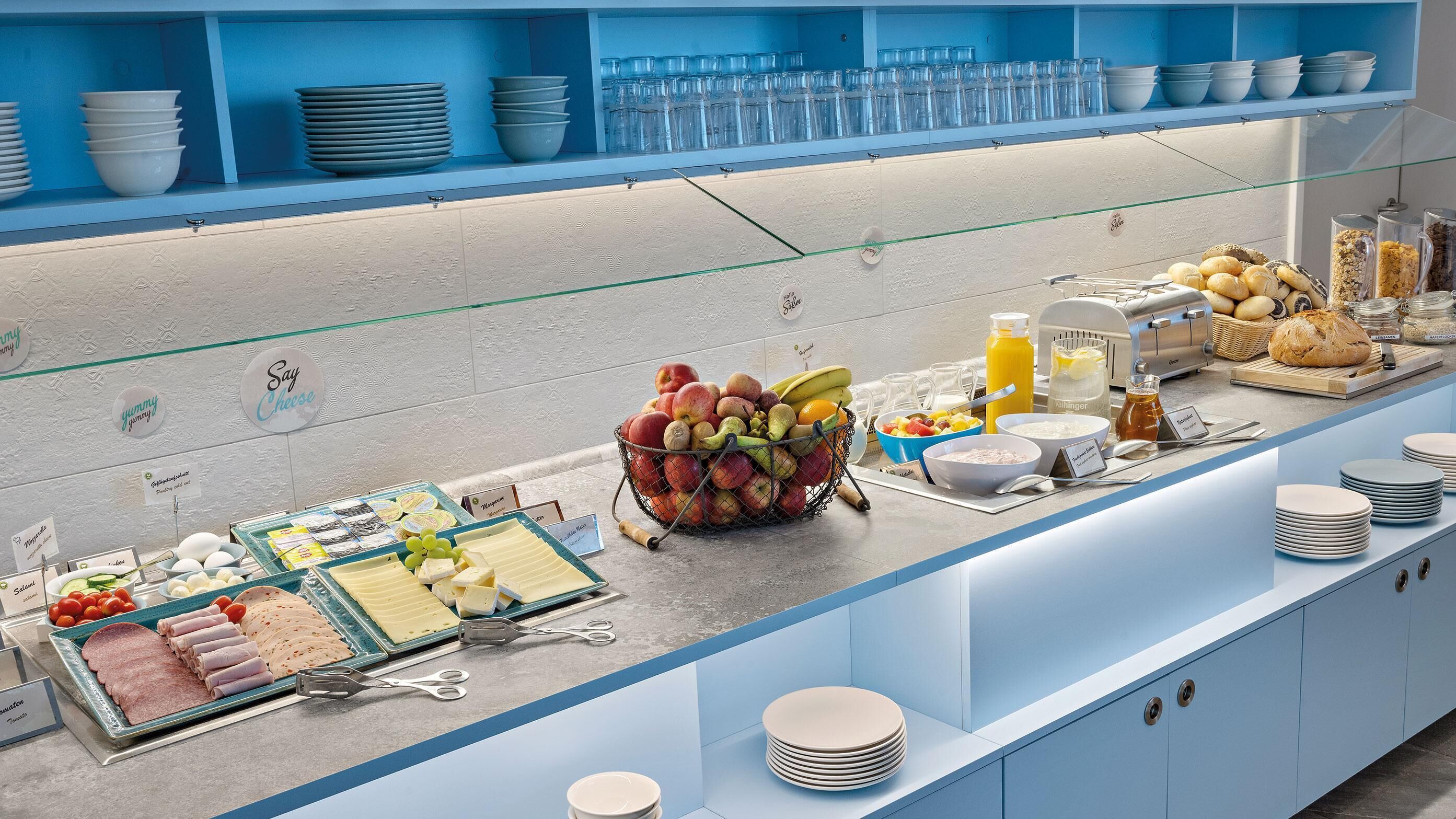 Un bufé con diversas opciones de comida, incluyendo frutas, quesos y pan.
