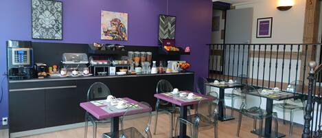 A modern breakfast area with purple walls, a coffee machine, and a variety of breakfast items.