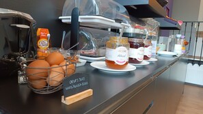 A breakfast display with hard-boiled eggs, jams, and a sign indicating the availability of fresh eggs.