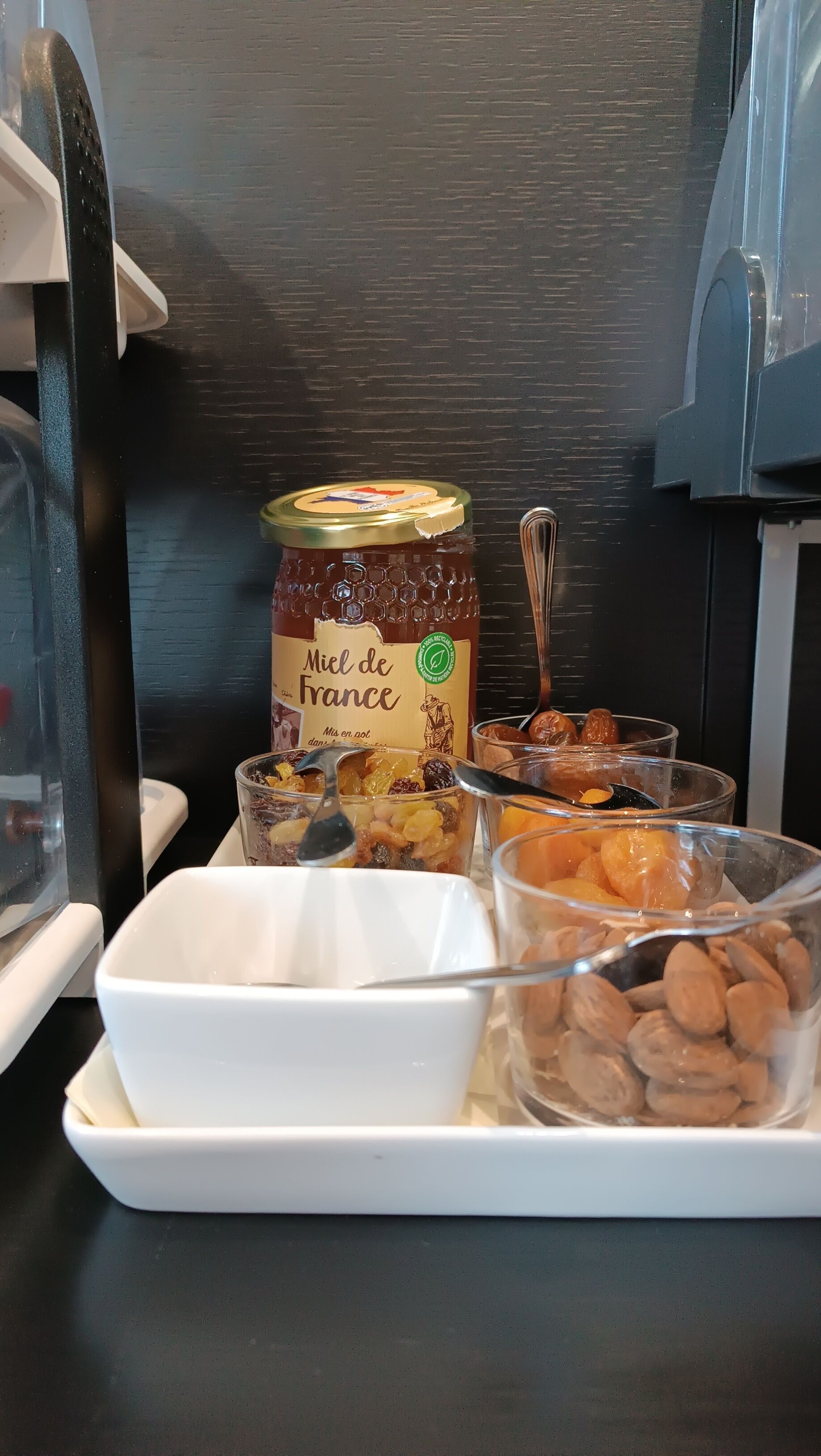 Un plateau avec un pot de miel de la marque « Miel de France », divers fruits secs et des fruits confits.