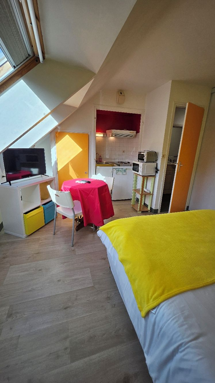 A compact room with a bed, a desk, and a small kitchenette.