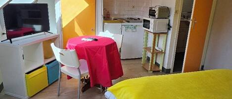 Una habitación funcional con cama, escritorio y una pequeña kitchenette.