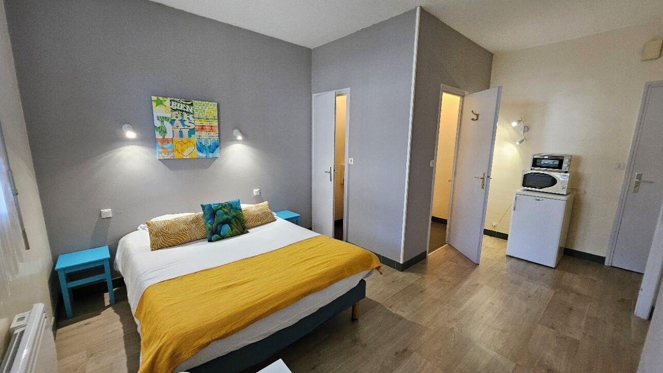 A bedroom with a bed, a nightstand, a dresser, and a microwave.