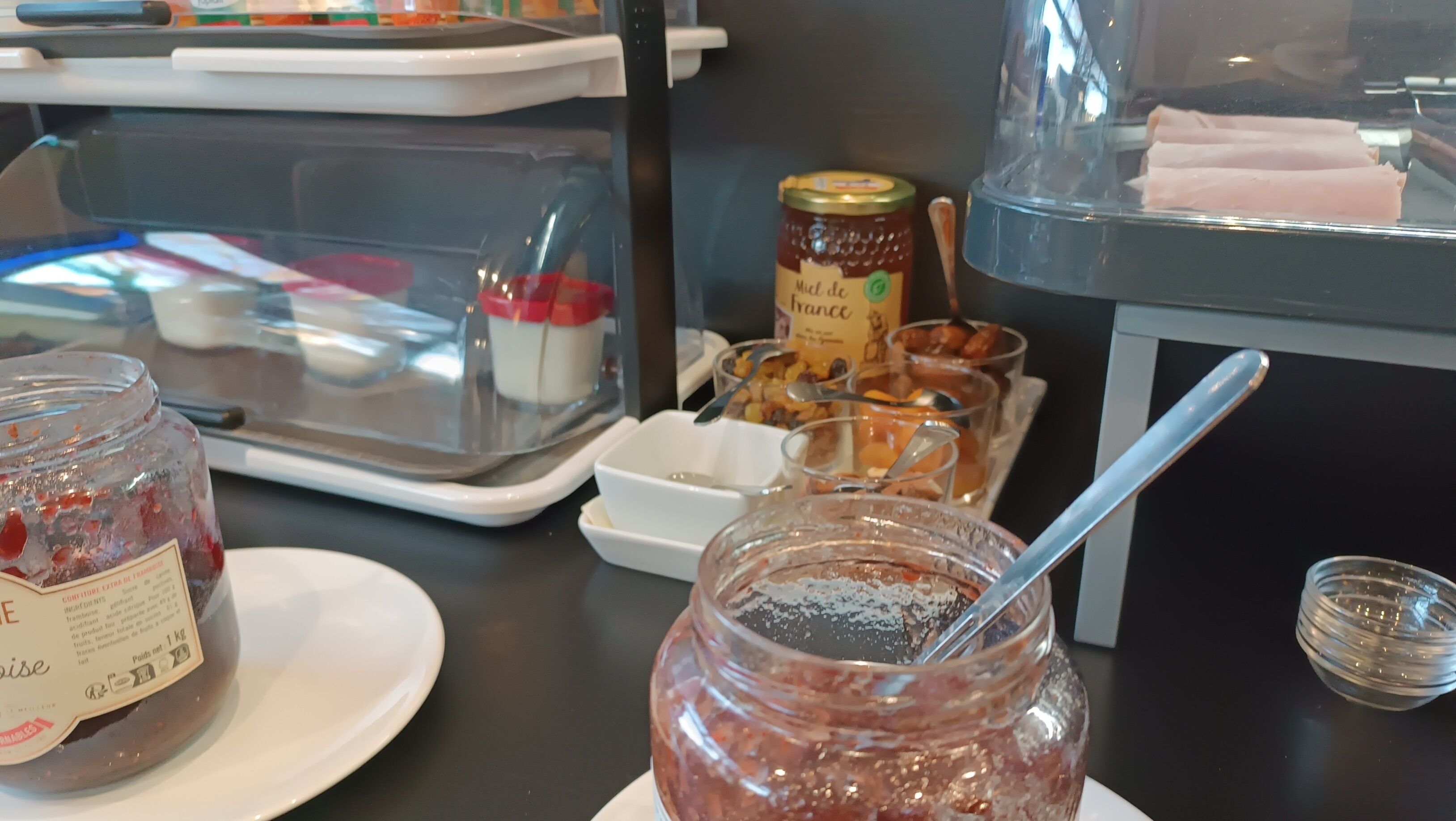 Una presentación de diversos alimentos, entre ellos frascos de conservas y una bandeja con frutos secos.