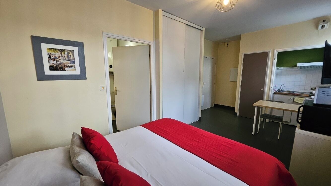 Una camera d'albergo con un letto, una scrivania e un angolo cottura.