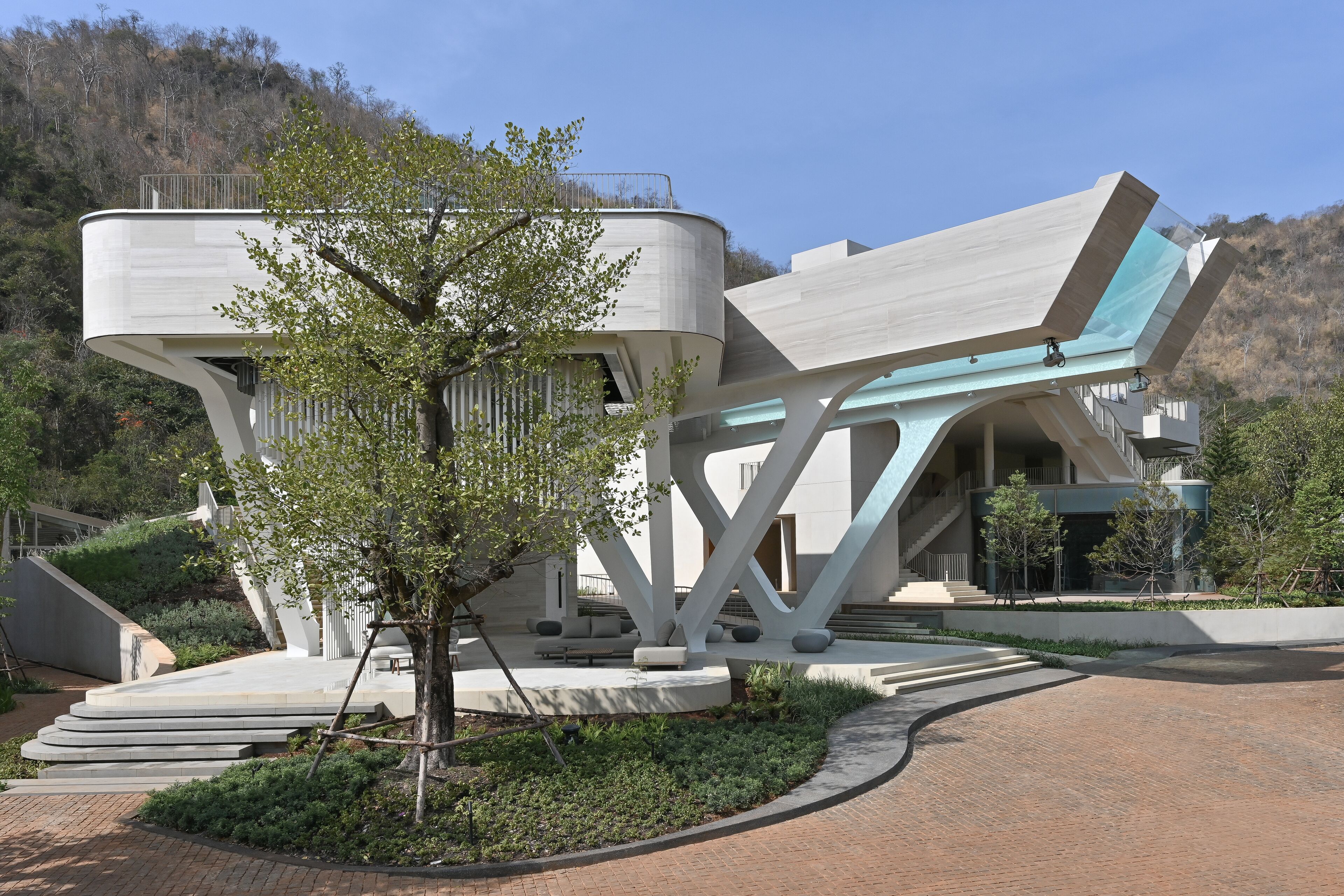A modern building with a unique architectural design, featuring a cantilevered section and a circular structure.