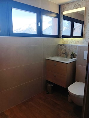 Ein kleines Badezimmer mit Fenster, Waschbecken und Toilette.
