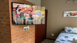 A TV mounted on a brick wall displaying a series titled "From Scratch."