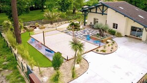 Un espace extérieur aménagé avec une terrasse, des sièges et un bâtiment doté d’un toit en pente.