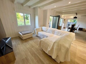 Une pièce comprenant un grand lit, un banc et un coin repas avec des chaises et une table.