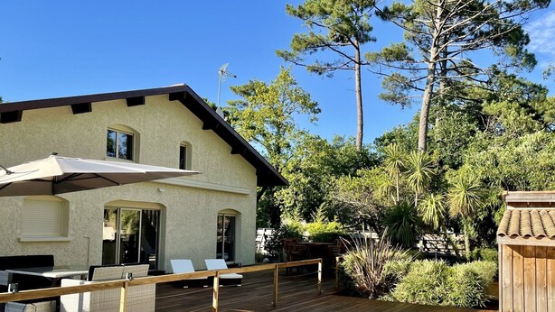 Una casa con piscina, terraza de madera y zona de estar al aire libre.