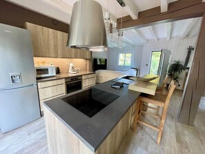 Een moderne keuken met een centraal eiland, roestvrijstalen apparatuur en hanglampen.