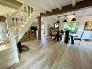 A spacious interior with a staircase, dining area, and large windows.