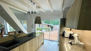 Una cocina moderna con una isla grande, electrodomésticos de acero inoxidable y un ventanal corredero que da a un espacio exterior.