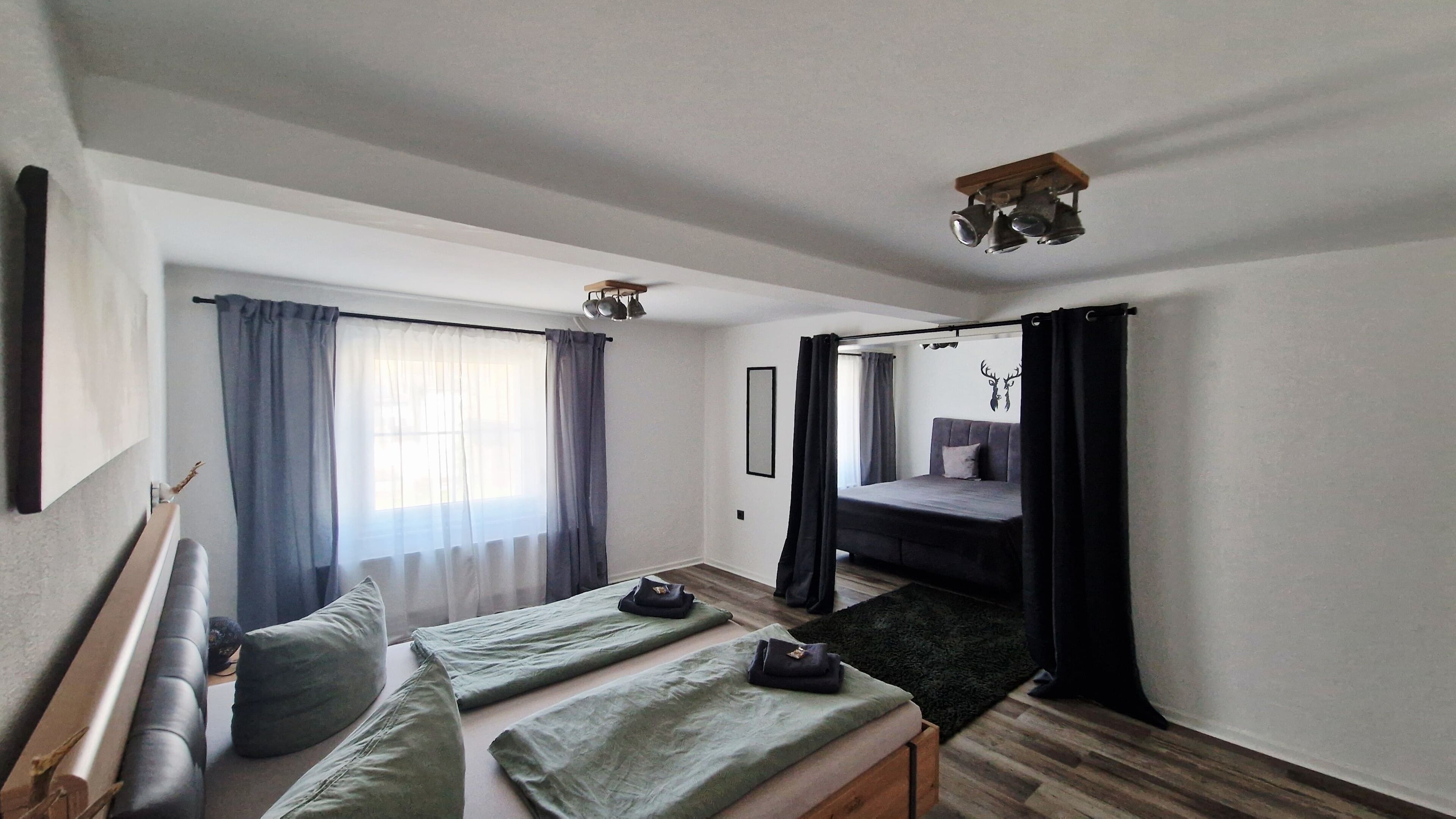 Une pièce comprenant un lit, un canapé, une petite table et une fenêtre avec des rideaux.