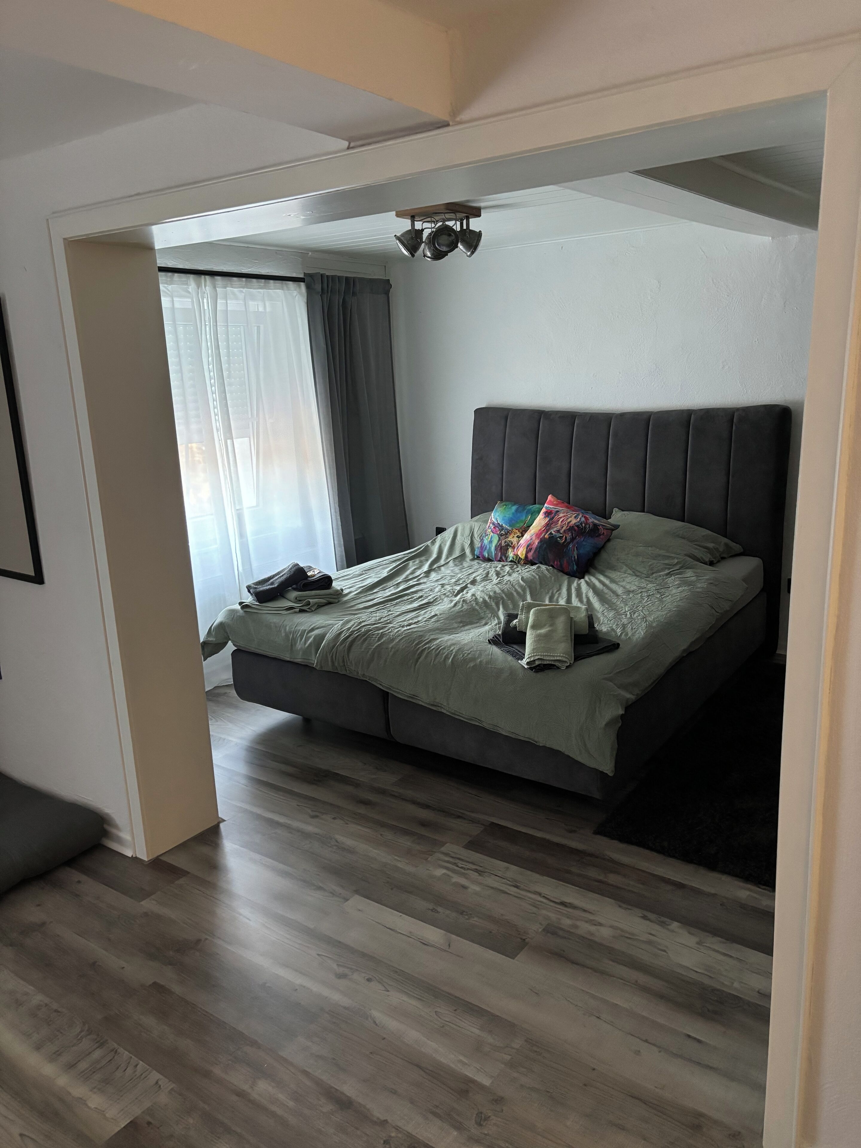 A bedroom with a bed, a window with curtains, and a ceiling light fixture.
