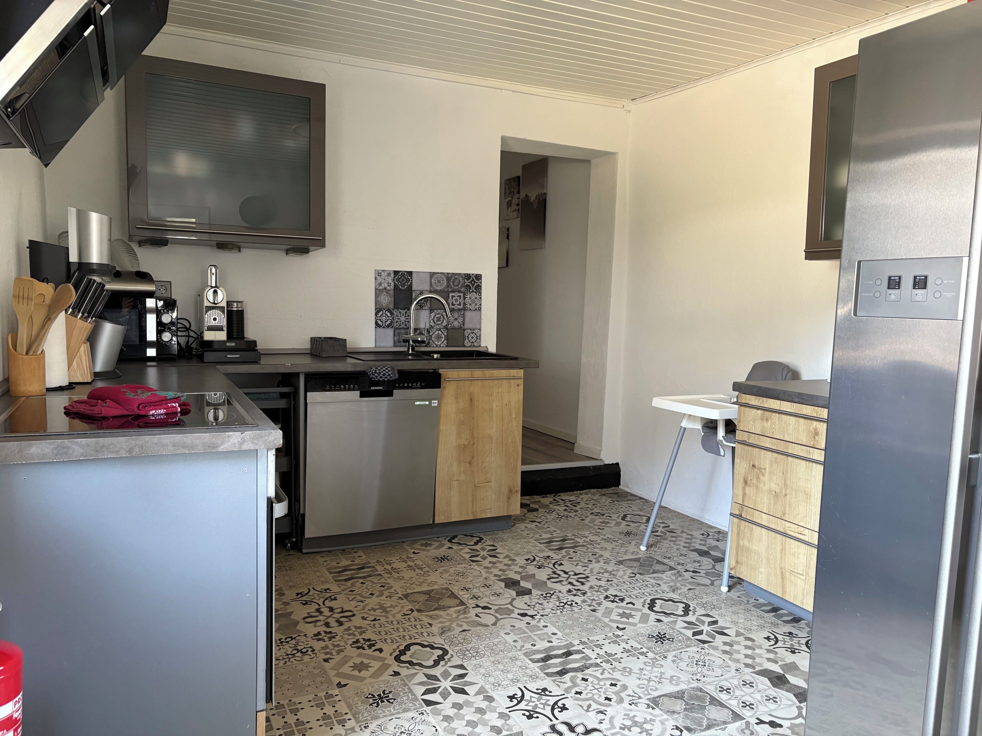 Una cucina moderna con elettrodomestici in acciaio inossidabile, lavastoviglie e pavimento in piastrelle decorate.