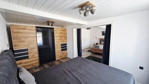 A bedroom with a bed, wardrobe, and a small kitchenette area.
