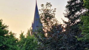 A park with a unique wooden bench and a church spire in the background.