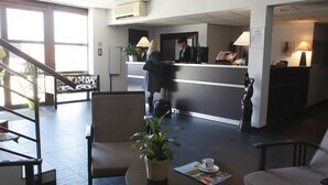 A hotel reception area with a reception desk, chairs, a staircase, and a potted plant. - Romantic Getaway in Carcassonne (Carcassonne)