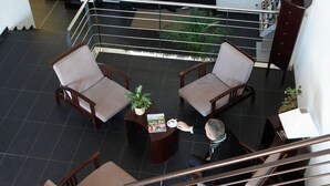 A spacious lobby with a high ceiling, a staircase, and a railing. There are two wooden chairs with cushions and a small table with a plant and a magazine. - Romantic Getaway in Carcassonne (Carcassonne)