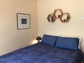 Ein Schlafzimmer mit einem Bett, einem gerahmten Bild an der Wand und einem sechseckigen Bücherregal.