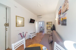 Uma sala de estar com sofá, televisão, mesa de centro e estante.