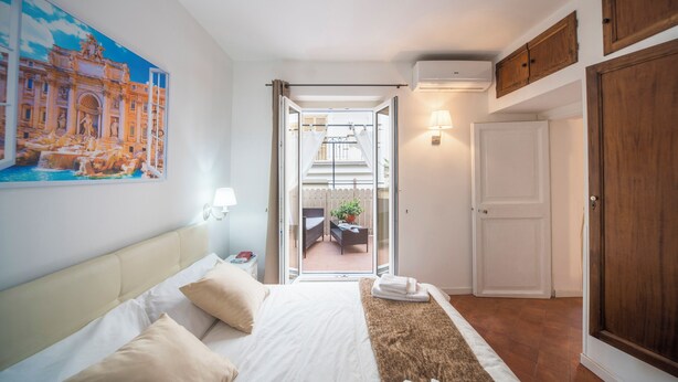 Une chambre d’hôtel avec un lit, un tableau, un balcon et une porte.