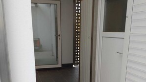 A narrow hallway with dark tiled flooring, white walls, and a door with a frosted glass panel. - Großzügige Ferienwohnung in Heßheim (Heßheim)