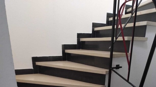 A staircase with alternating black and beige steps, leading to a landing. - Großzügige Ferienwohnung in Heßheim (Heßheim)