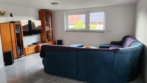 A living room with a blue sofa, a wooden cabinet, and a television. - Großzügige Ferienwohnung in Heßheim (Heßheim)