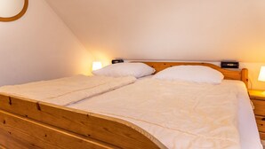 A single bed with a wooden frame and white bedding in a room with sloped ceilings.