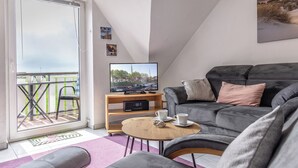 A modern living room with a grey sofa, a coffee table, and a television on a wooden stand.