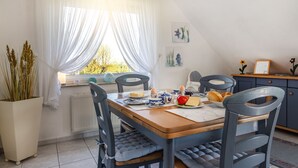 A dining area with a wooden table, blue and white plates, and a potted plant.