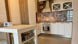 A kitchen with white cabinets, a tiled backsplash, and a built-in oven. - Sozopol Green life Apartment (Созопол)