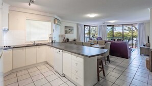 Una cucina moderna con isola centrale, mobili bianchi e zona pranzo con divano e sedie.