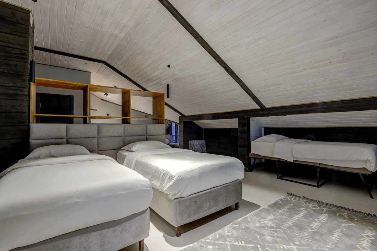 A modern bedroom with two large beds, a built-in bench, and a small TV.