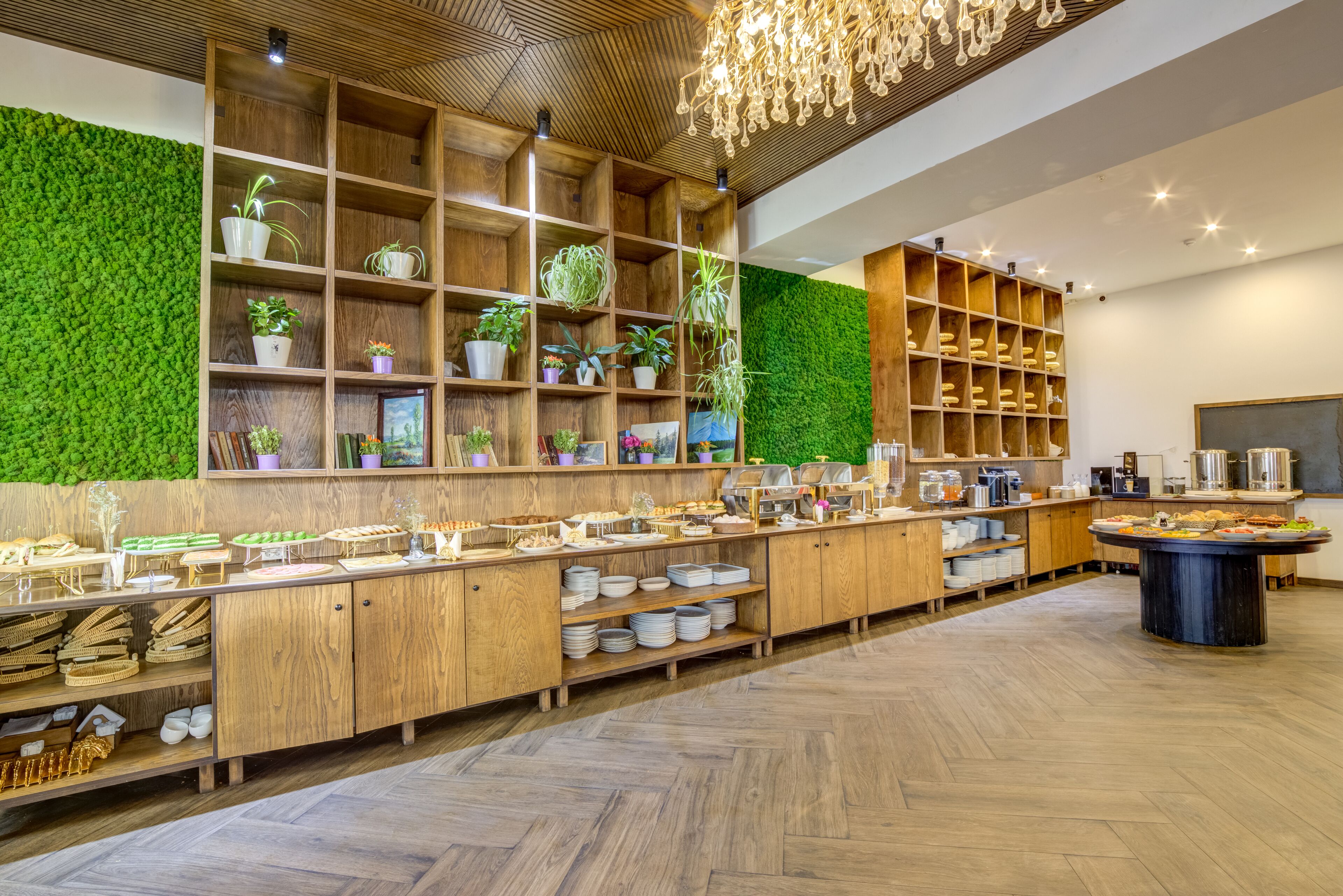 A modern kitchen with wooden cabinets, a green wall, and a central island with a round table.
